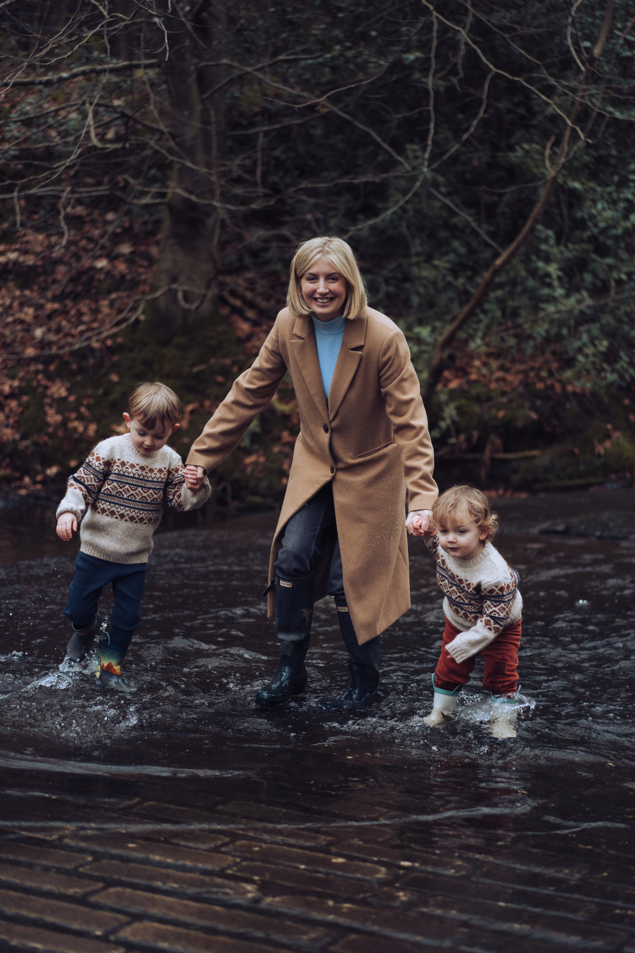 Kate Taylor walking through a woodland stream with her two young sons